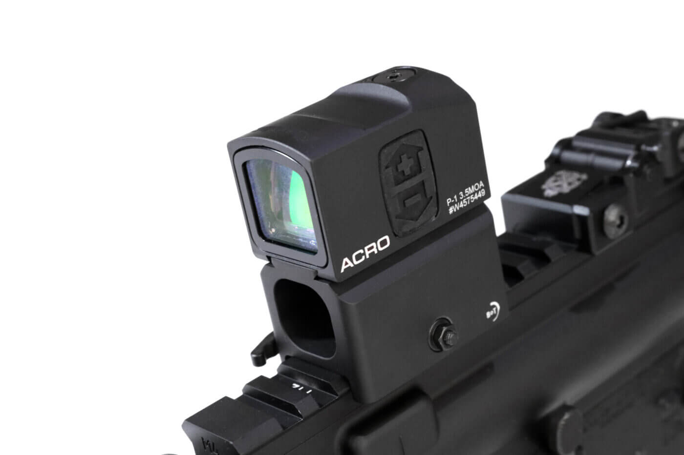 In this photo, we see the writer mounted the red dot sight on his SAINT rifle for the Aimpoint ACRO P-1 review. The optic is mounted on a riser on the Picatinny rail. The rear iron sight is visible.