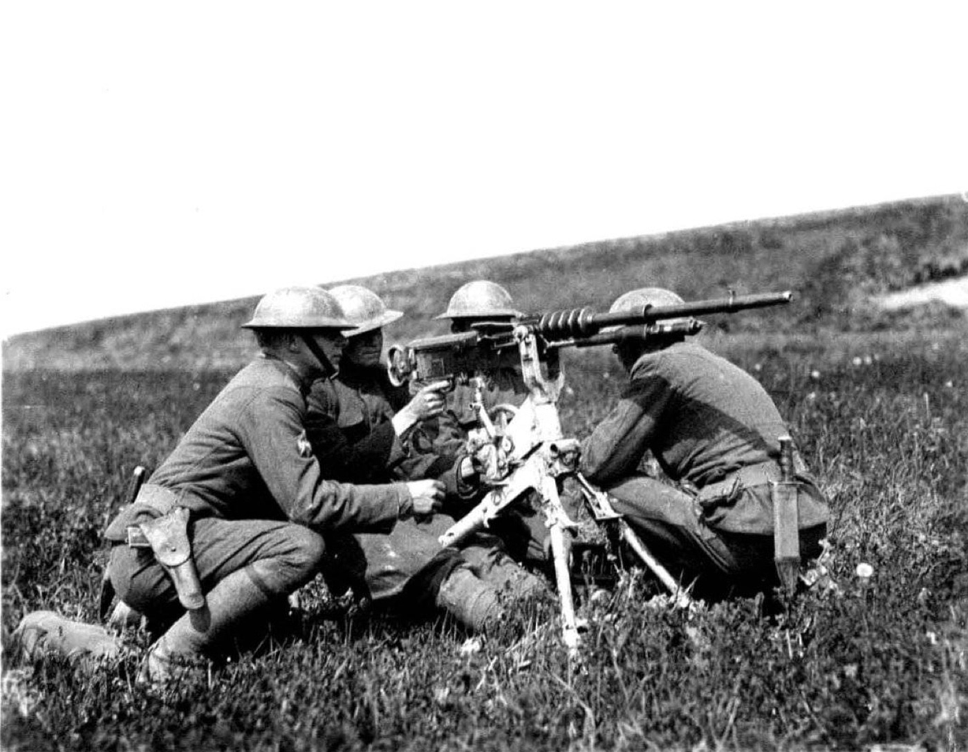 A U.S. Army machine gun team is captured in this photo. They are operating a Hotchkiss m1914 standard machine gun at a firing range in France during May 1918. The four man team recently arrived in Europe to support the British and French Army during World War I. You can see the gun's tripod and ammo feed strips.