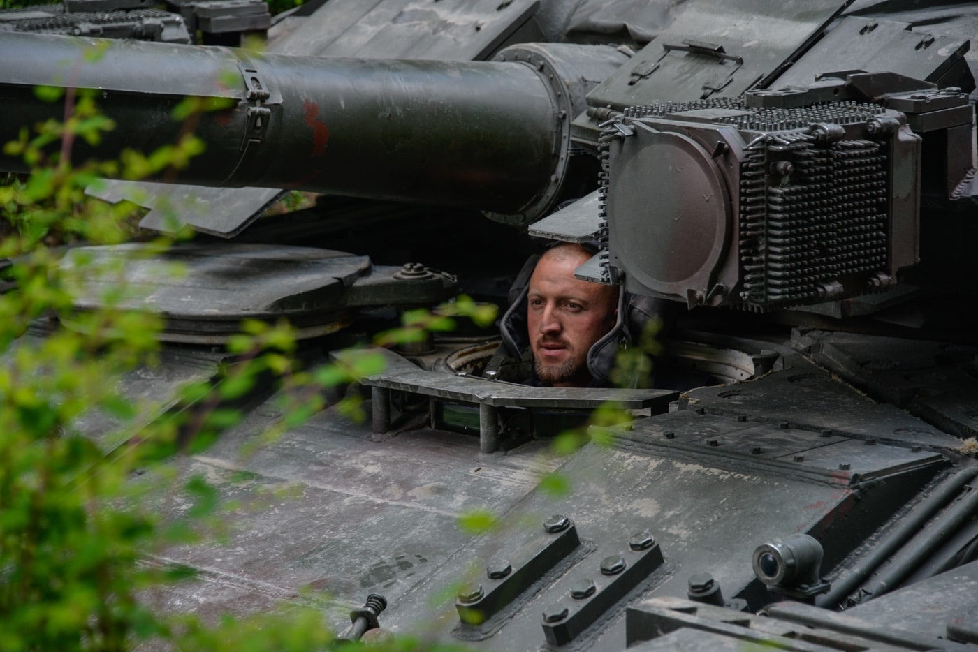 A Ukrainian T-84 tank driver peers out of his hatch as he maneuvers his tank into a defensive position. The heavy armor of the tank protects the crew but also limits visibility.