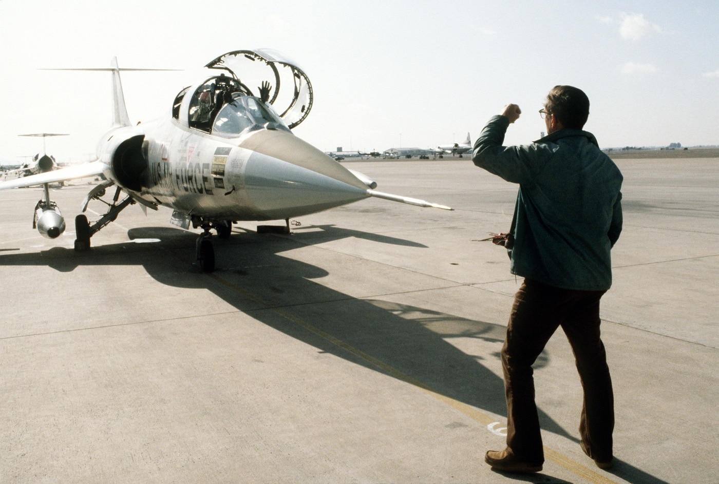 In this color photograph, we see a U.S. Air Force crew chief directs an F-104G Starfighter fighter plane onto the runway during the training of German pilots by the 69th Tactical Fighter Training Squadron in 1982.