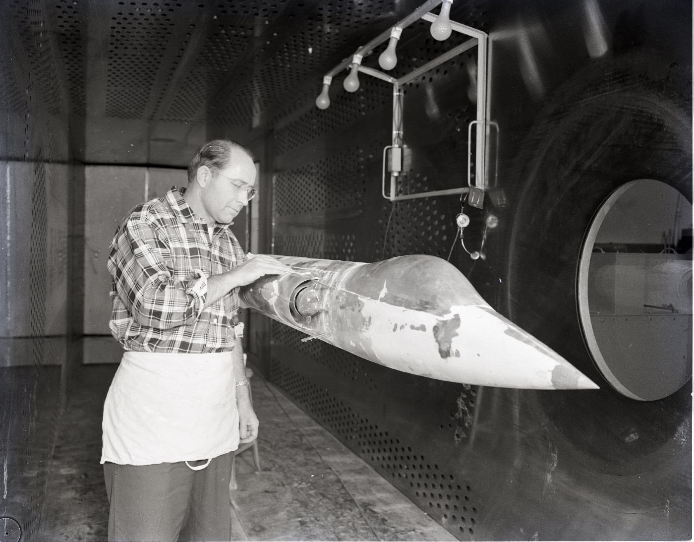 In this black and white digital photograph of aerospace engineers working with a scale model of the Lockheed F-104 Starfighter. Developed by Lockheed — later Lockheed Martin — the Starfighter was the first two-seat General Electric aircraft to set an altitude record and world speed record on its first flight when named the XF-104 or YF-104A. Both the Tactical Air Command and Flight Research Center saw a great deal of potential when the aircraft first flew. 