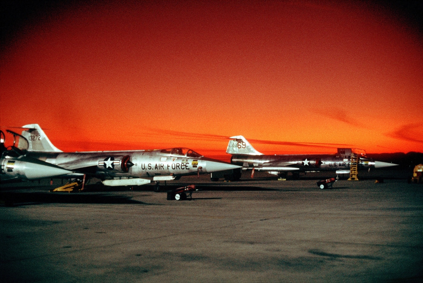 In this photo we see several F-104G fighters parked on the flight line at sunset.  The Lockheed F-104 Starfighter is an American single-engine, supersonic interceptor which was extensively deployed as a fighter-bomber during the Cold War.