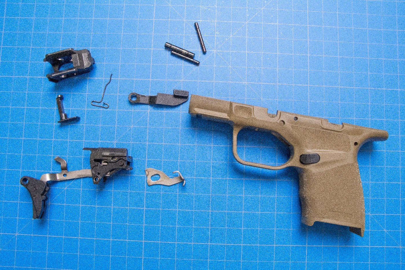 In this photo, we see where a prepper disassembled a Springfield 9mm pistol. We see the trigger assembly, slide stop, pins and other parts next to the polymer frame.