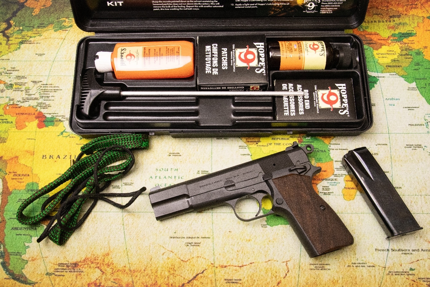 In this full color photograph we see a Springfield sa-35 9mm semi-automatic pistol with a Hoppe's cleaning kit. The gun and the kit are sitting on a large cleaning map that has a political map of the Earth on it. The sa-35 is based on the original P-35 handgun designed by John Moses Browning. The gun is better known as the Browning Hi Power. It is a single-action firearm that many people say is superior to the M1911A1.