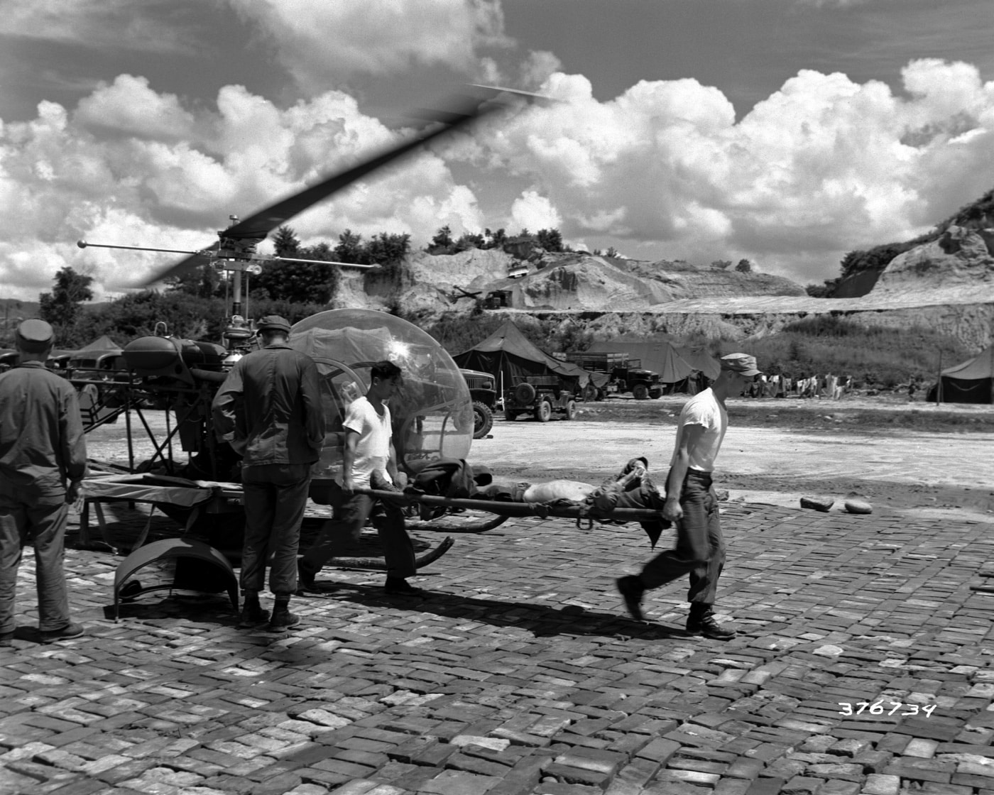 wounded soldier arrives at mobile army surgical hospital by Bell H-13 air ambulance