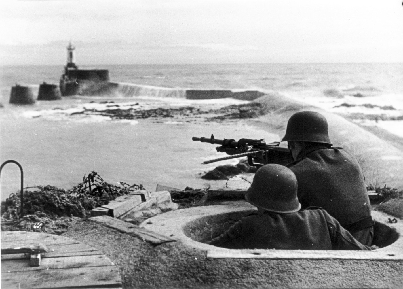 German soldiers shoot Hotchkiss M1914 machine gun from a Tobruk pit in the Atlantic Wall