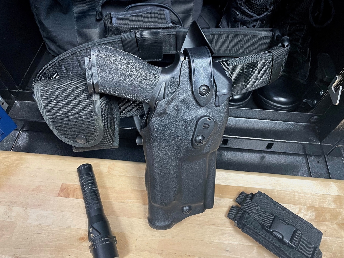 Shown here is a police duty belt with a weapon retention holster — the Safariland 6360RDS. Also seen are police handcuffs and a tactical flashlight.