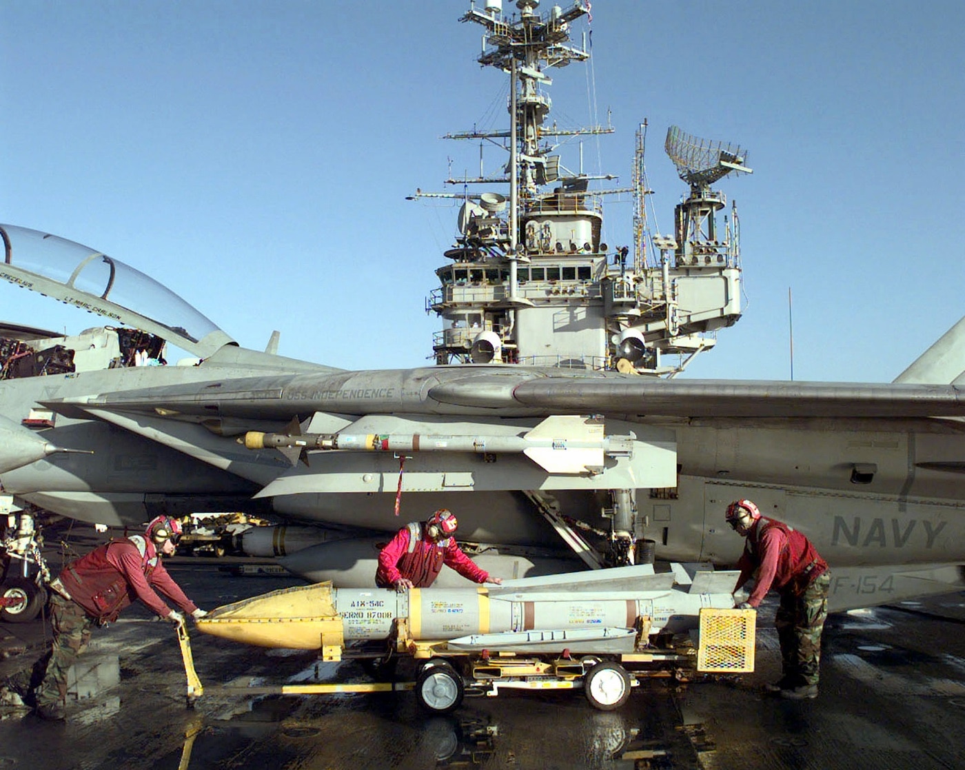 sailors load a Phoenix missile on an F-14 underway on the USS Independence