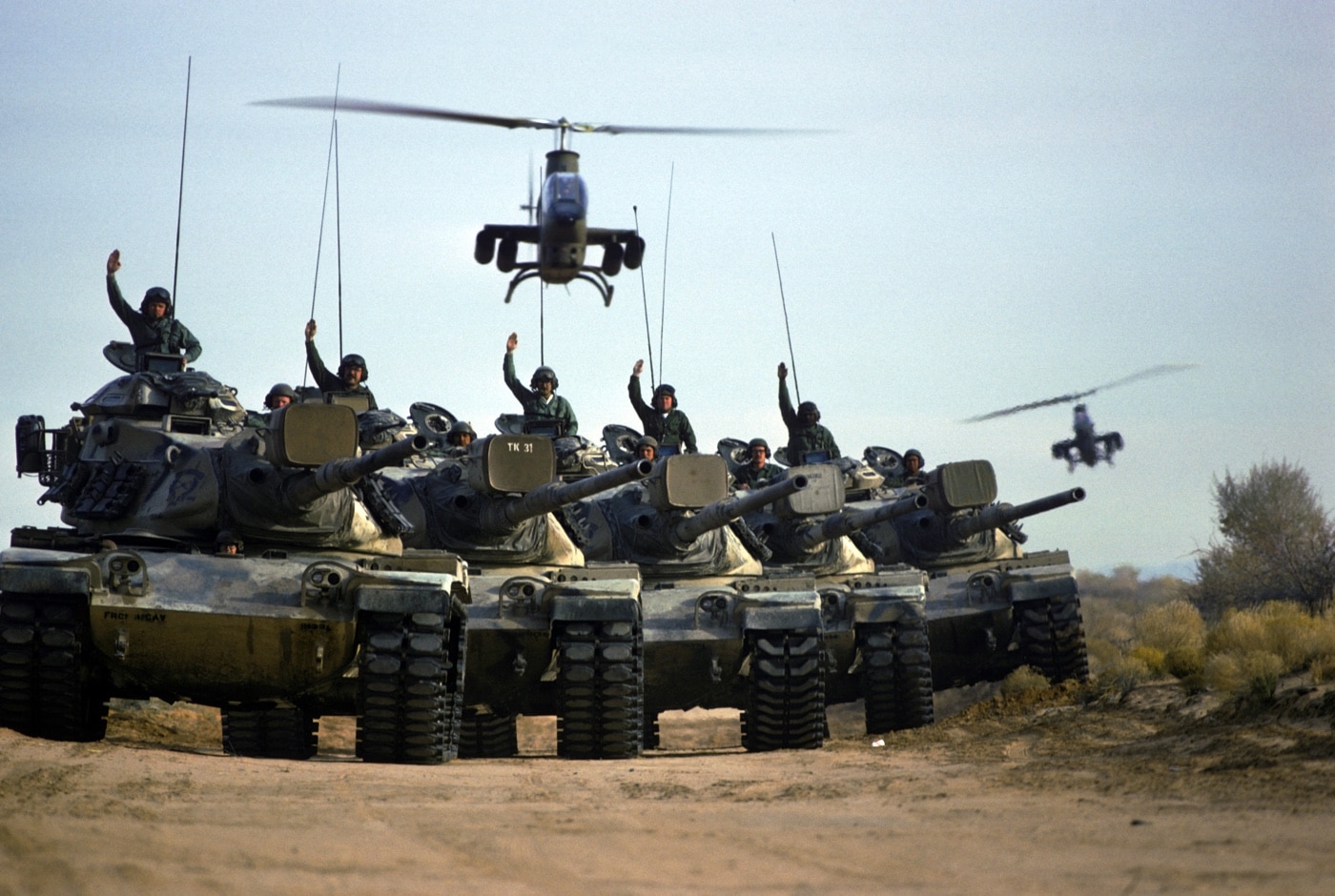 United States Army M-60 tanks in formation AH-1 Cobras overhead