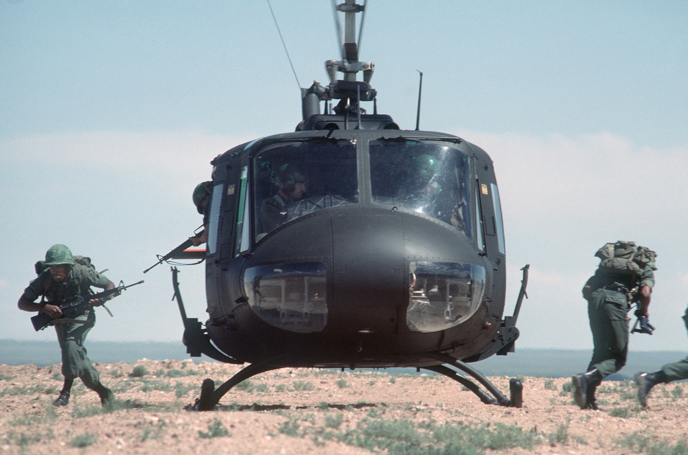 United States Army soldiers jump out of a Huey during a training exercise