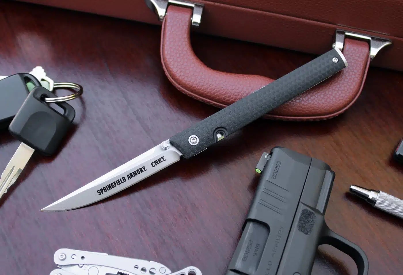 CRKT CEO knife with briefcase car keys and Springfield Armory Hellcat semi-automatic pistol