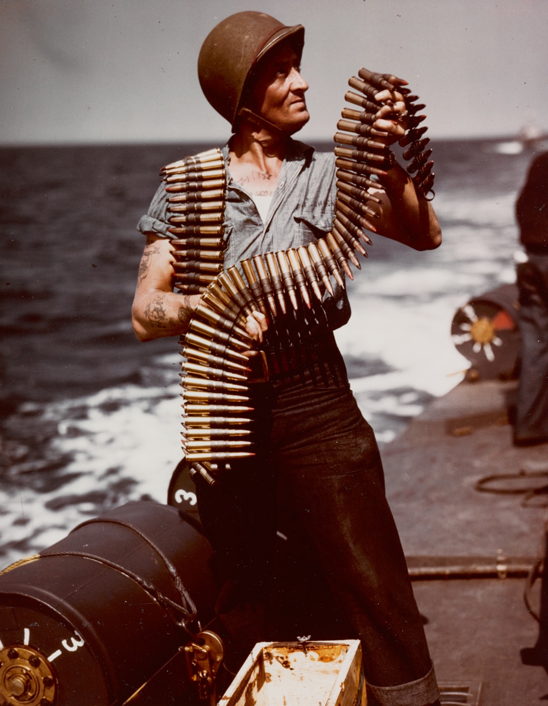 US Navy sailor loads 50 BMG ammunition on a PT boat during World War II