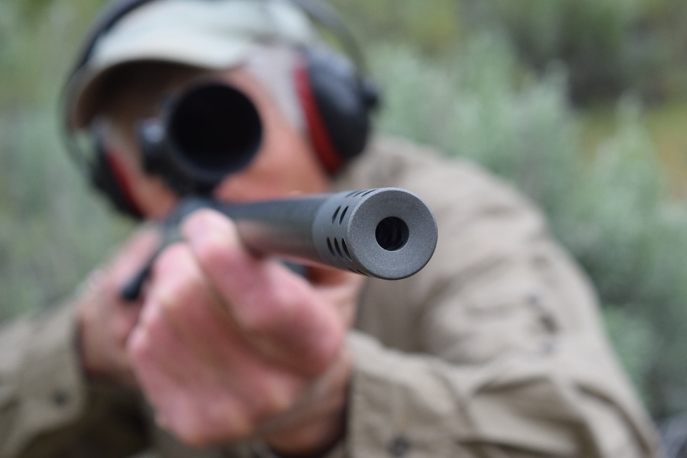 author aiming Boundary rifle at whitetail deer during hunting on grasslands