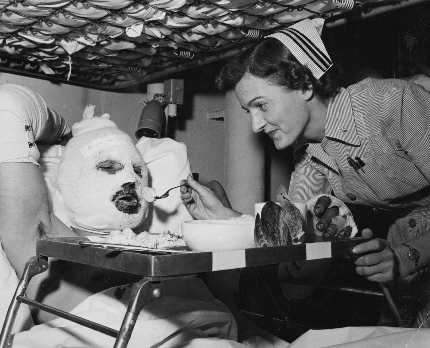 wounded US Marine is fed Thanksgiving dinner by nurse on USS Repose hospital ship