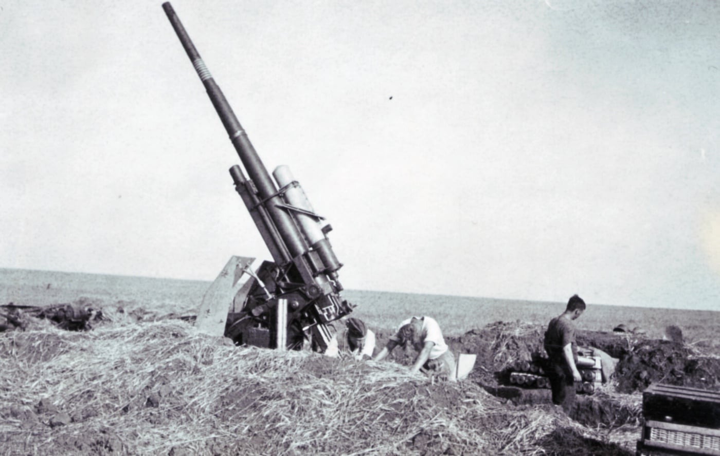 An 88mm flak gun is shown in a field, strategically positioned to defend against Allied bombers while also capable of engaging enemy tanks. The gun is surrounded by earth walls, with bunkers dug into them to store ammunition securely. Its dual-purpose role in anti-aircraft and anti-tank operations showcases its importance on the battlefield. This scene emphasizes the ingenuity and adaptability of German defenses during World War II.