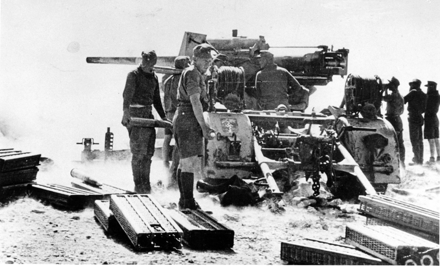 During a fierce battle with the British Army in North Africa, German soldiers operate an 88mm gun. Known for its effectiveness as a tank-killer, the gun’s firepower proved decisive in engagements across the desert terrain. The soldiers' movements reflect their training and the gun’s strategic importance in combating Allied armor. This scene highlights the 88mm’s pivotal role in German successes during the North African campaign.