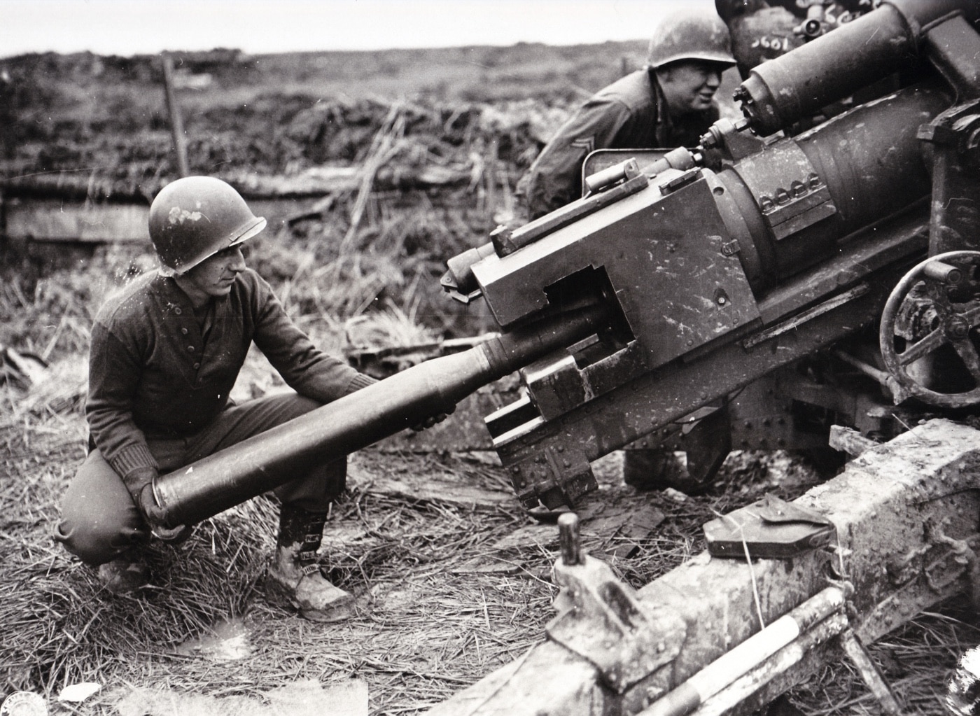 An American soldier inspects a captured German Pak 43 anti-tank gun, focusing on a 23-pound shell positioned nearby. The large-caliber weapon, known for its effectiveness against Allied armor, represents a key component of Germany’s defensive arsenal. The soldier’s examination highlights the Allies’ efforts to understand and counter German engineering. This image underscores the scale and power of the artillery used in World War II tank battles.