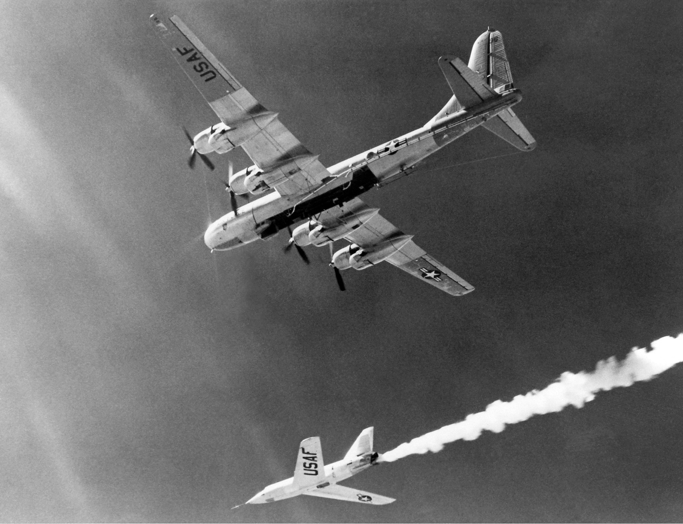 The Bell X-2 rocket plane is shown mid-drop from its Boeing B-50 Superfortress mothership during a test flight in the 1950s. This experimental aircraft was designed to explore supersonic speeds and high-altitude performance. The image captures the dramatic moment of release, a critical phase in testing. This program helped advance knowledge of aerospace engineering and extreme flight conditions during the Cold War era.