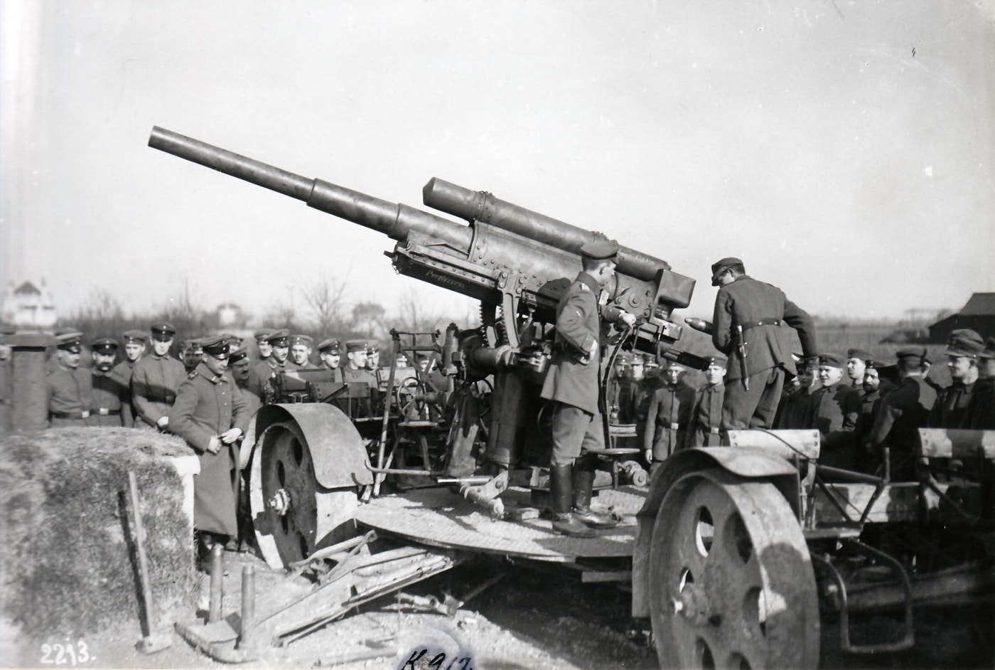 German soldiers during World War I are seen loading an 8.8 cm FLAK 16 anti-aircraft gun near the front lines. The crew works methodically, demonstrating the preparation required to fire the large artillery piece. The gun, designed for high-altitude targeting, stands prominently as the soldiers perform their tasks with precision. This scene captures the early use of anti-aircraft weapons in combat, reflecting both innovation and the intensity of wartime conditions.