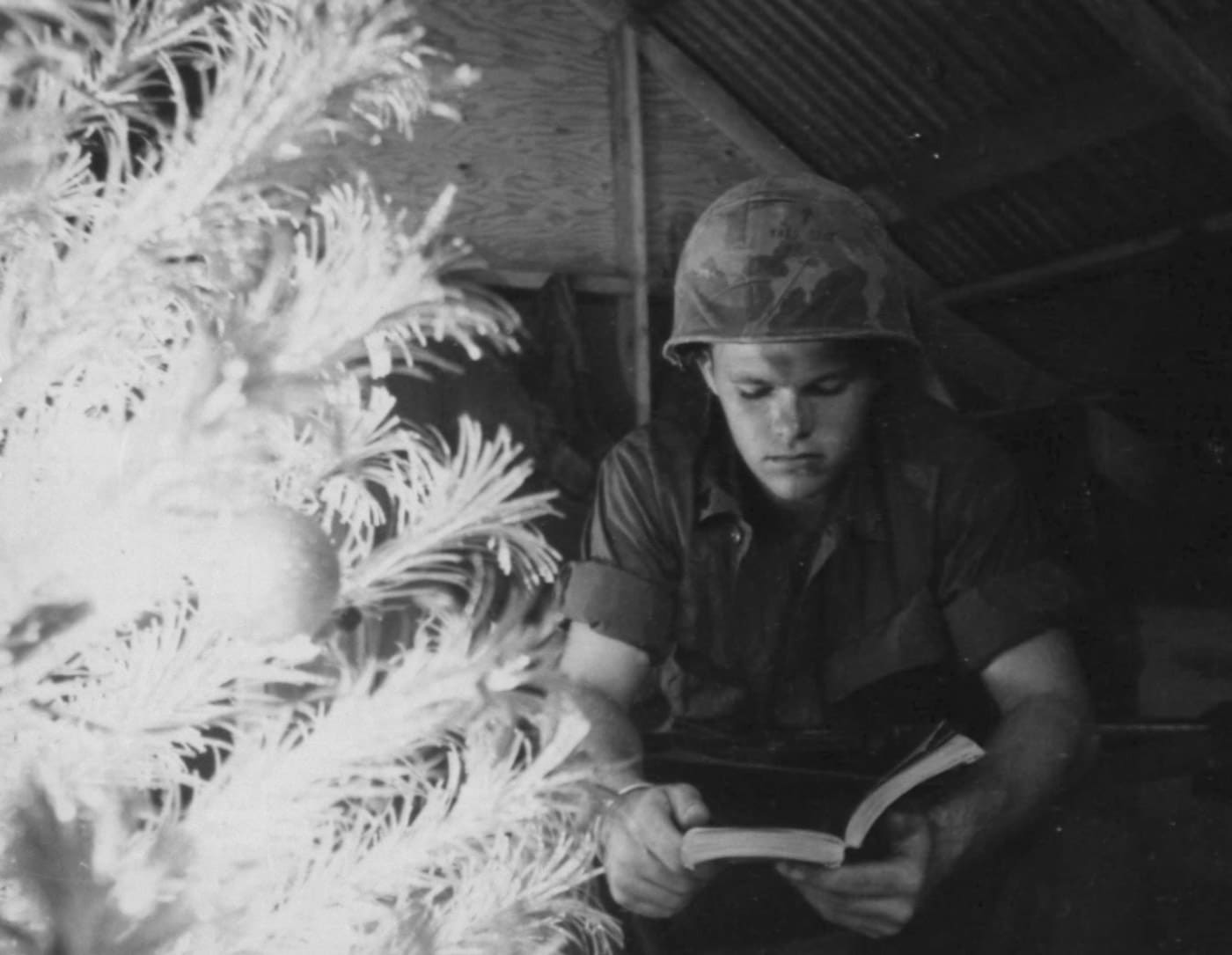 Marine Corporal Larry Nabb reads next to a Christmas tree December 1968 in Vietnam War