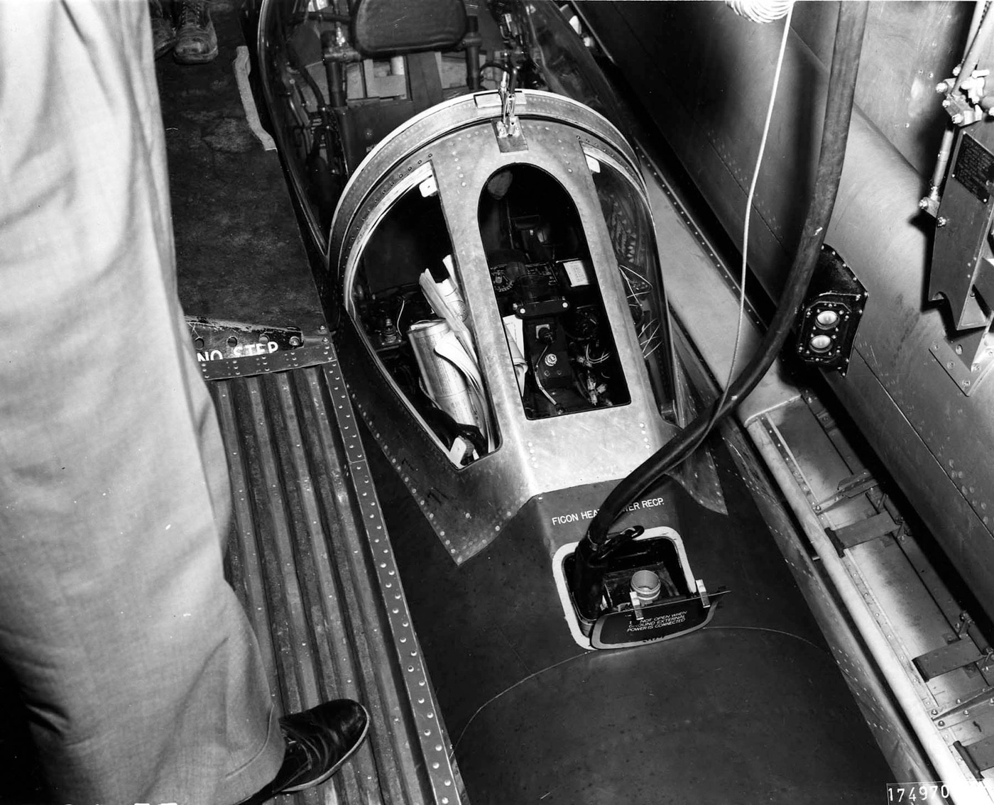 The photo shows the YRF-84F fighter jet as seen through the interior of the B-36 Peacemaker bomber. The image highlights the experimental design that allowed pilots to access the YRF-84F cockpit from inside the massive bomber. This innovation was part of a mid-air docking system designed to launch and retrieve the parasite fighter. The photo reflects the cutting-edge aviation concepts tested during the Cold War.