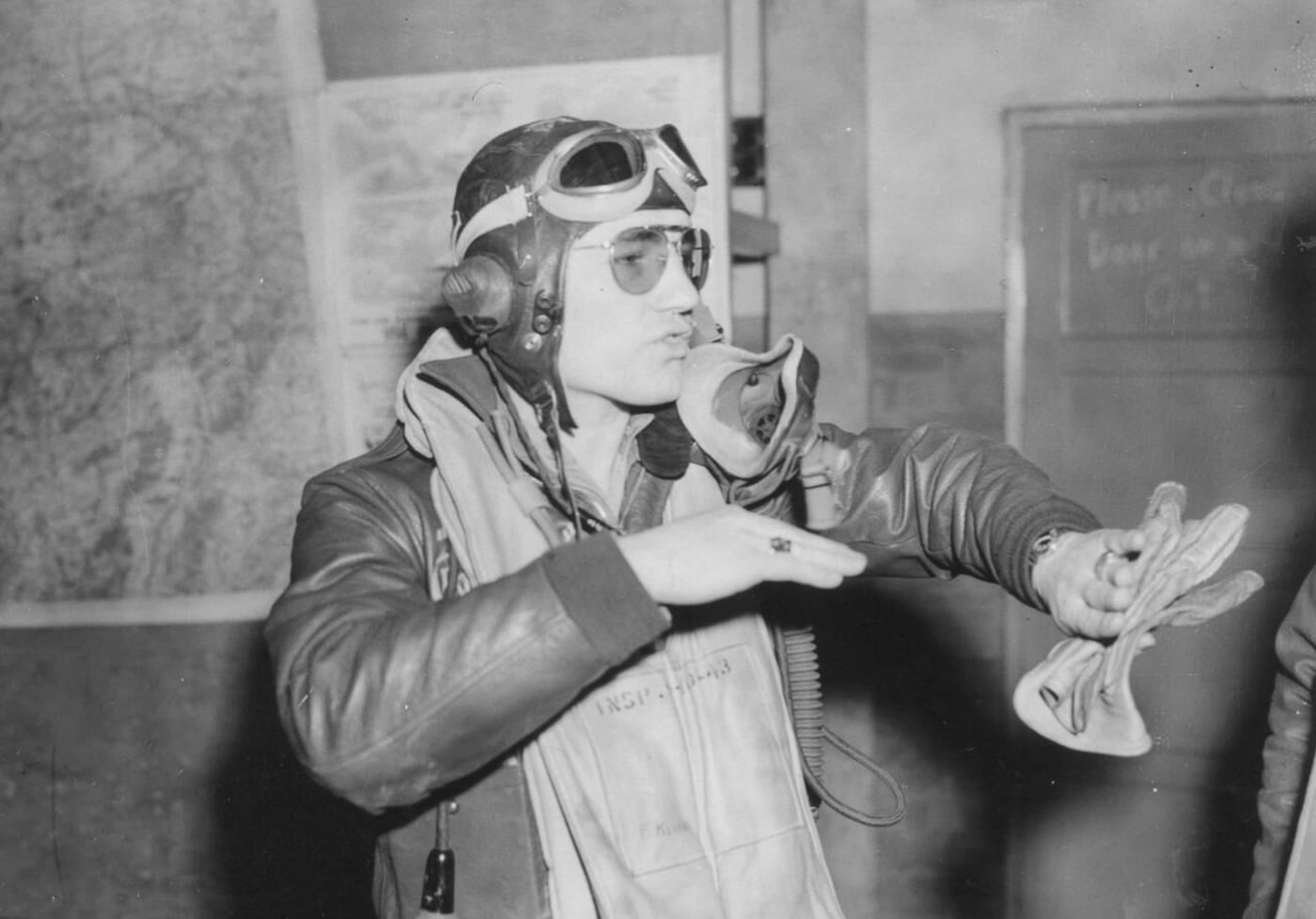 A P-47 Thunderbolt pilot enthusiastically shares his story, waving his hands like he’s still in the cockpit. You can almost hear him say, “Then I banked hard, and bam! Got him right in my sights!” His excitement is infectious, and his grin says, “Just another day at the office — if your office is the sky.” Somewhere, his audience is thinking, “Can we buy this guy a drink already?”