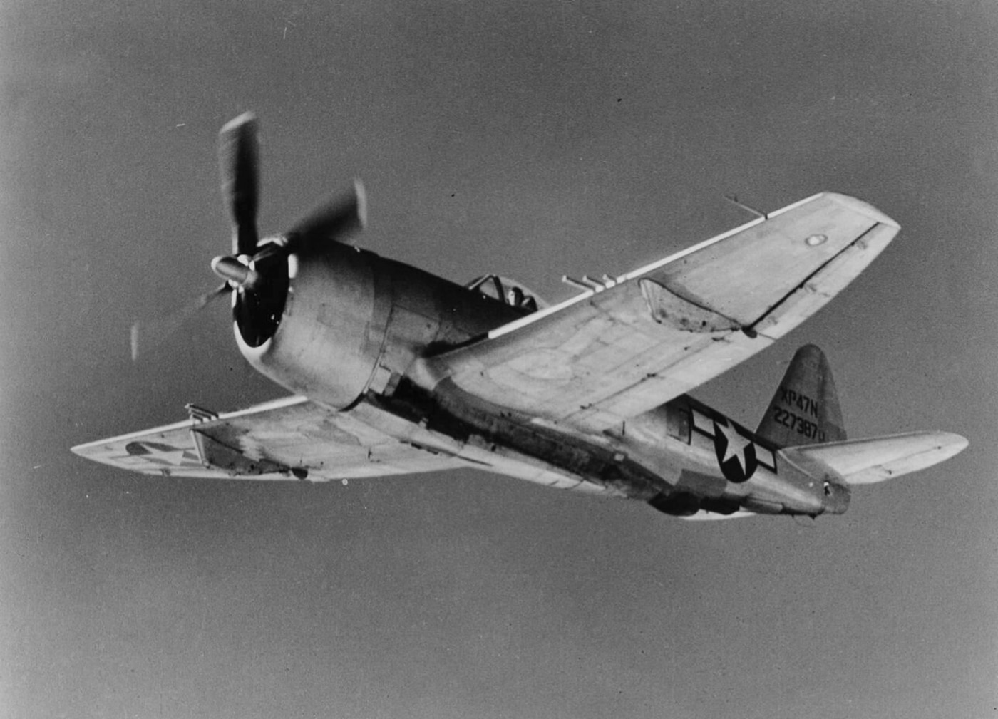 The Republic XP-47N flies gracefully, showcasing its extended wingspan and design modifications that distinguish it from the standard P-47 Thunderbolt. Built for long-range missions, this experimental variant represented a leap forward in engineering. The image captures the sleek lines of an aircraft designed to expand the operational reach of the Allied air forces. This test flight demonstrates Republic Aviation’s pursuit of continual improvement in military aviation.