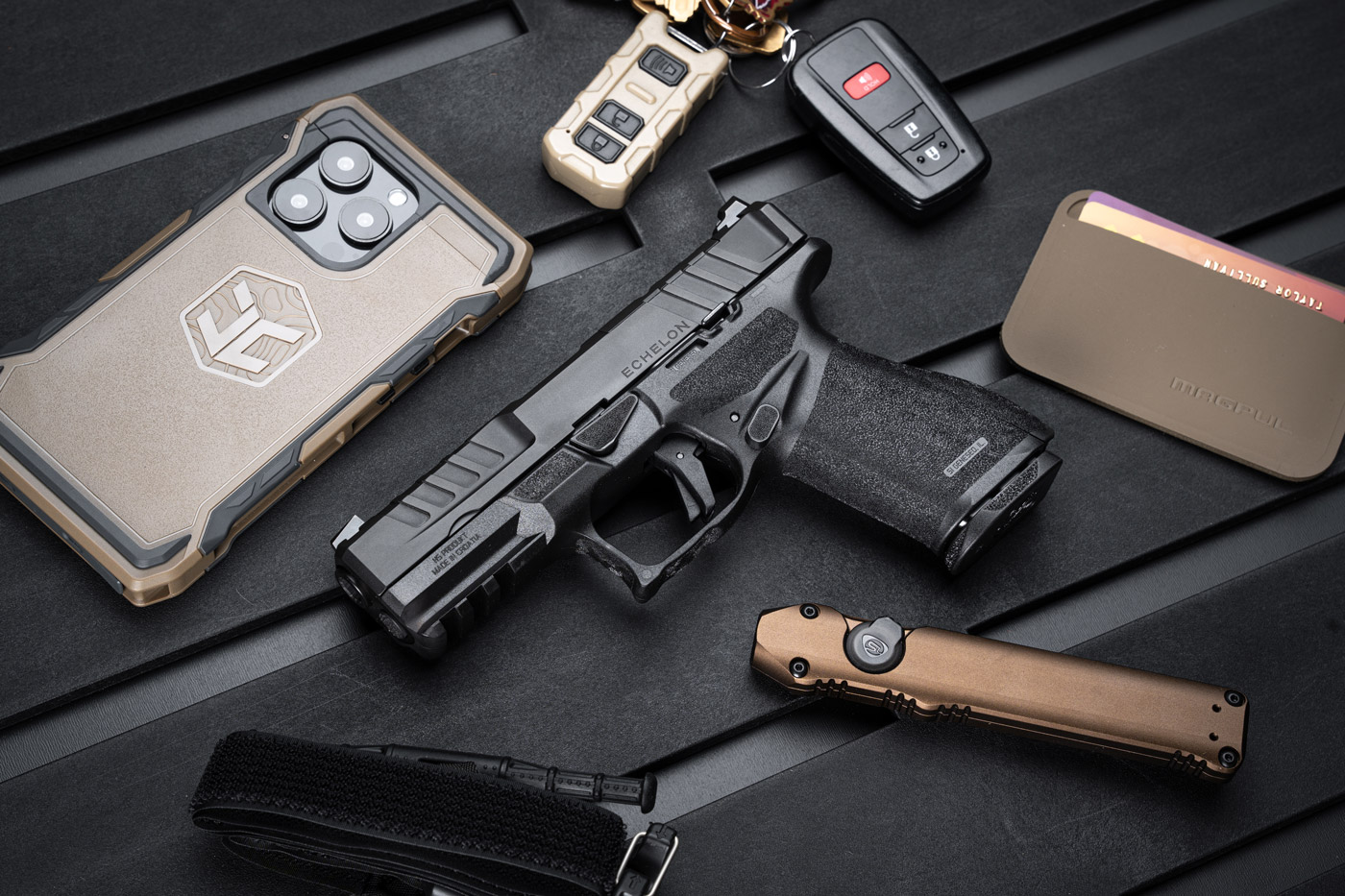 The Springfield Armory Echelon 4.0C compact 9mm pistol is displayed alongside everyday carry (EDC) gear, including a tactical flashlight, folding knife, and a durable wallet. This setup highlights the pistol's role as a practical and reliable choice for concealed carry and personal defense. The compact size, ergonomic grip, and versatile design of the Echelon 4.0C align perfectly with the needs of EDC enthusiasts seeking performance and portability in their tools.