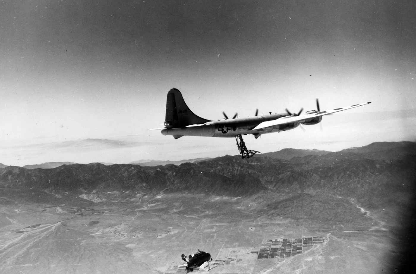 The McDonnell XF-85 Goblin is captured mid-deployment as it drops from the underside of a B-29 Superfortress bomber. The tiny parasite fighter, designed to launch in flight, detaches from its housing to test its ability to defend the bomber. This image highlights the innovative yet challenging engineering of late 1940s aviation experiments. The Goblin’s compact size contrasts with the massive bomber, showcasing the bold concept of airborne fighter deployment.