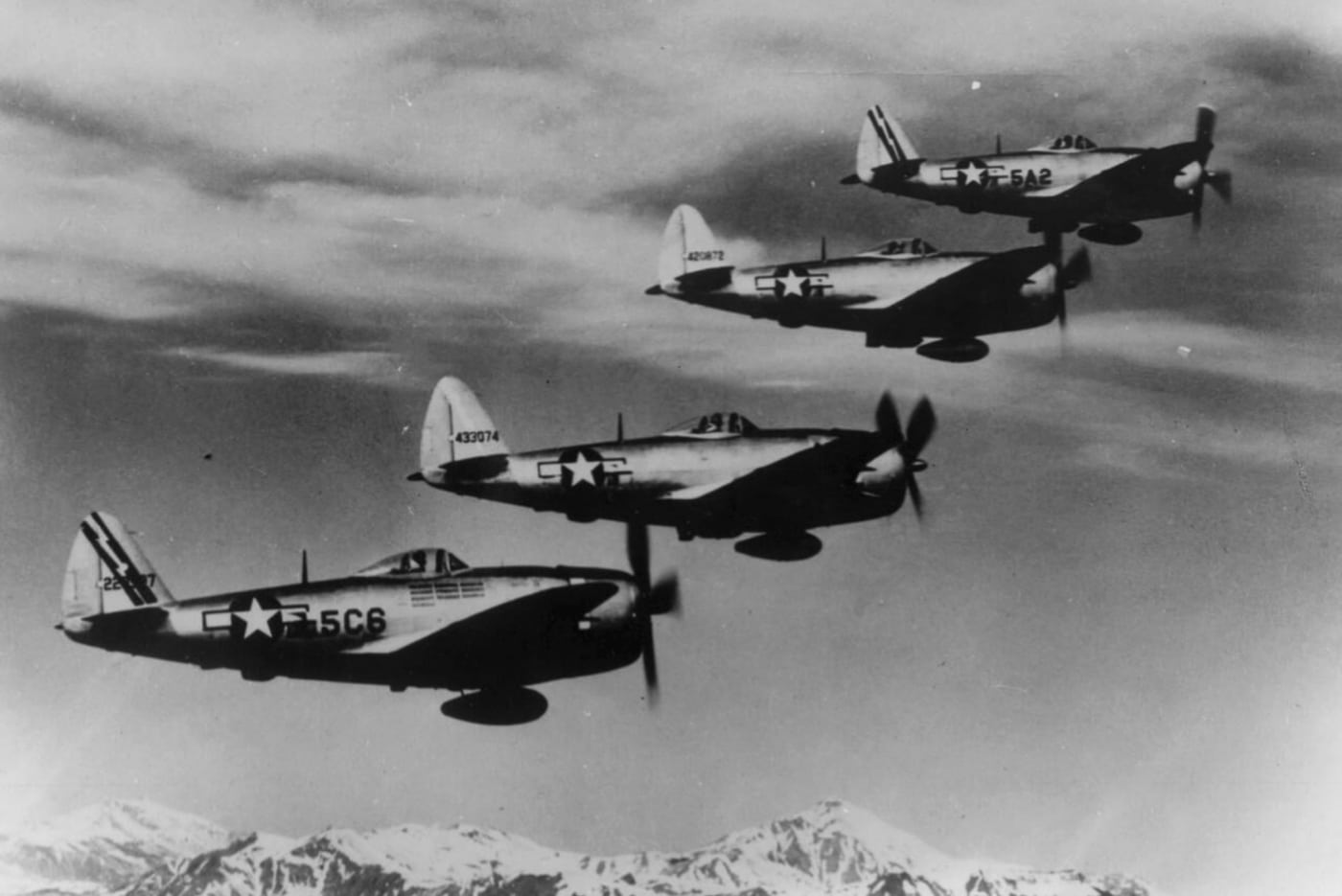 A squadron of bubbletop Republic P-47D Thunderbolts glides over the dramatic peaks of Italy’s Appenine Mountains like a flock of very determined eagles. Their bubble canopies shine in the sunlight, giving pilots a panoramic view — and probably a killer sunburn. These machines are not just flying; they’re strutting, showing off their teamwork and power. It’s like synchronized swimming, but with bombs and machine guns!