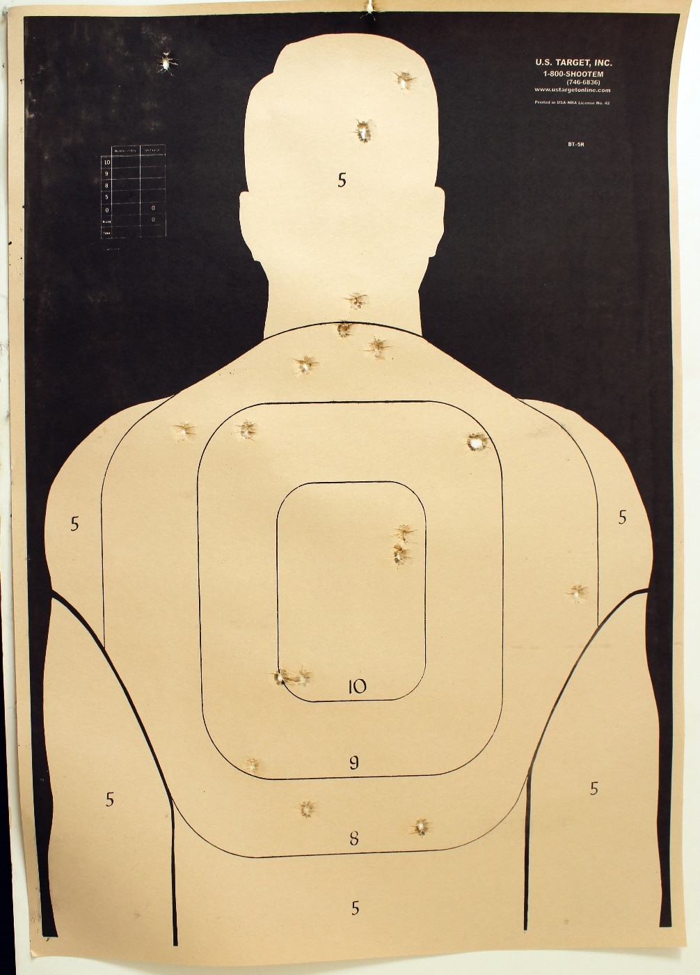 A paper target with bullet holes displayed at a shooting range, highlighting wide shot dispersion caused by recoil anticipation. The pattern suggests the shooter struggled with maintaining consistent control during live fire. Correcting such issues requires deliberate and focused training, including dry fire practice. This target serves as a visual example of the challenges shooters face at the range.