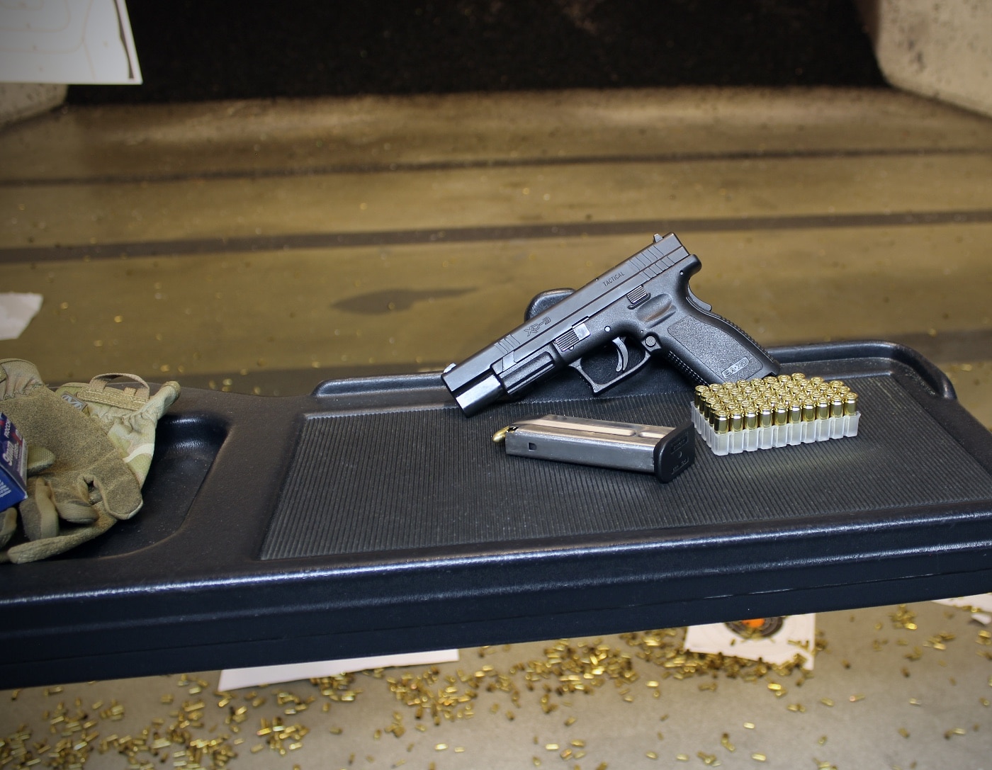 A 9mm pistol resting on a shooting bench at a range, emphasizing the importance of integrating dry fire into live-fire sessions. Range-based dry fire practice bridges the gap between at-home training and real-world shooting. This method helps shooters overcome mental compartmentalization of trigger control skills. Regular range practice ensures consistent and accurate shooting habits.