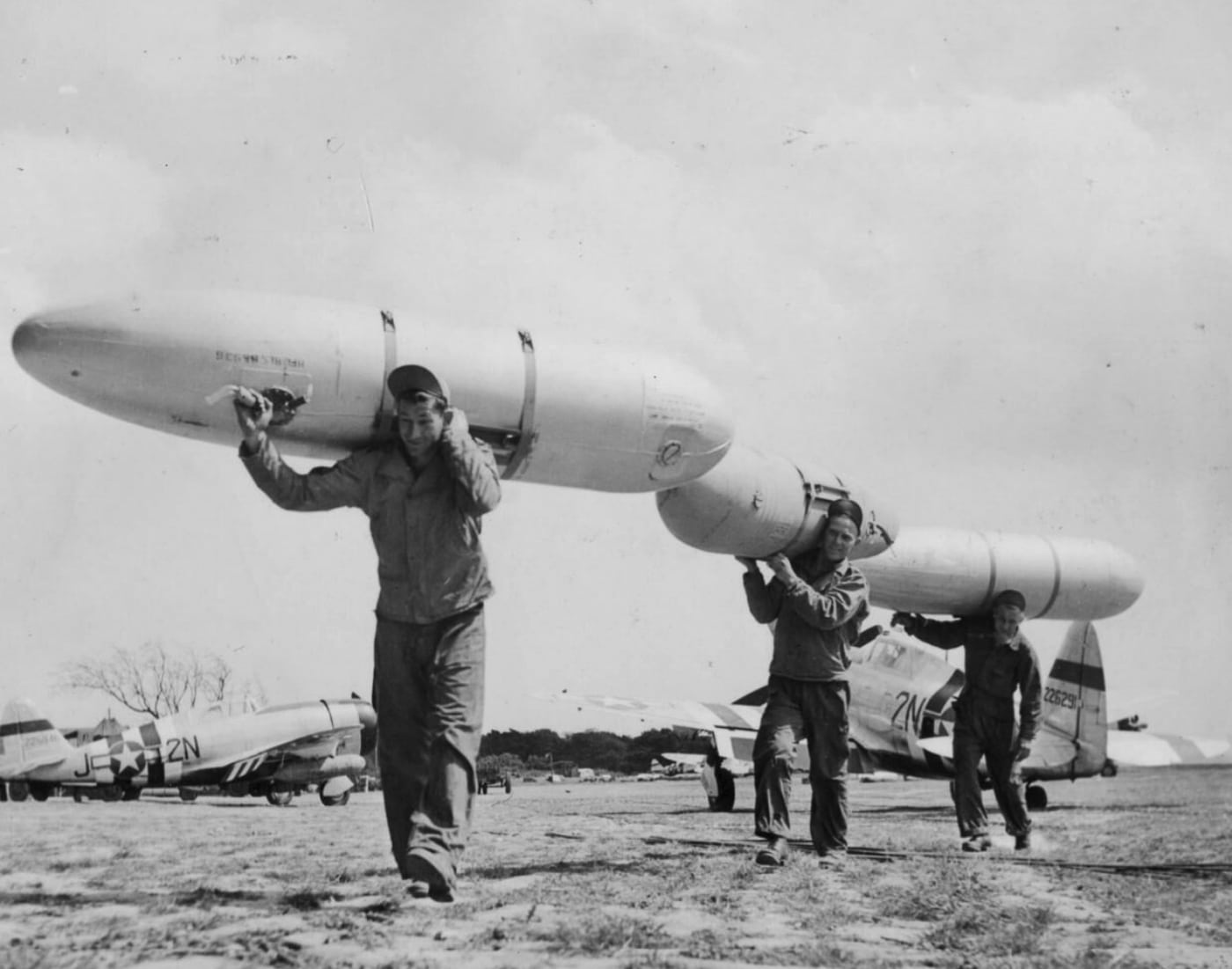 Three members of the 50th Fighter Group, Staff Sergeants Anthony Petroski and Matthias Culley, and Sergeant Elmer Martens, haul fuel drop tanks used by P-47 Thunderbolts at a 9th Air Force base. The 108-gallon tanks, vital for long-range missions, were often repurposed for creative uses like sleeping bunks and storage. This image reflects the ingenuity of ground personnel in adapting equipment to meet wartime needs. Their efforts ensured the operational readiness of the Thunderbolt fleet.