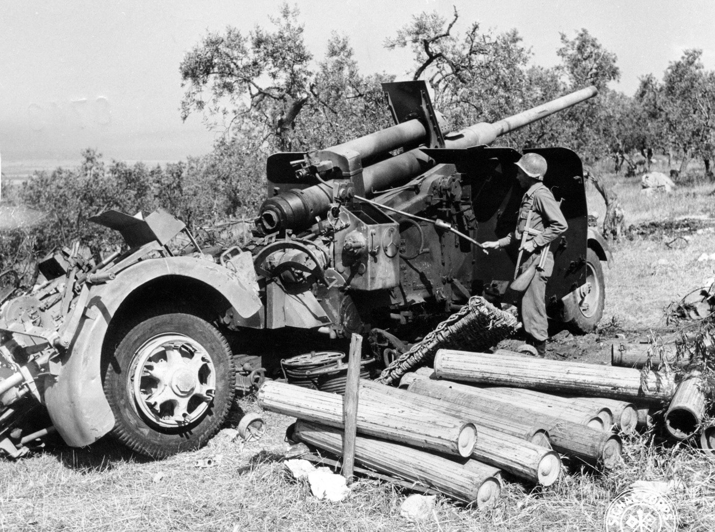 A late-variant German 88mm Flak 41 gun is seen captured by U.S. Army soldiers in Italy during World War II. The imposing weapon, designed for long-range anti-aircraft and anti-tank roles, stands silent after fierce battles. The soldiers inspect the advanced artillery piece, reflecting on its significance in German defensive strategies. This image highlights the Allies' efforts to overcome and analyze formidable German technology.