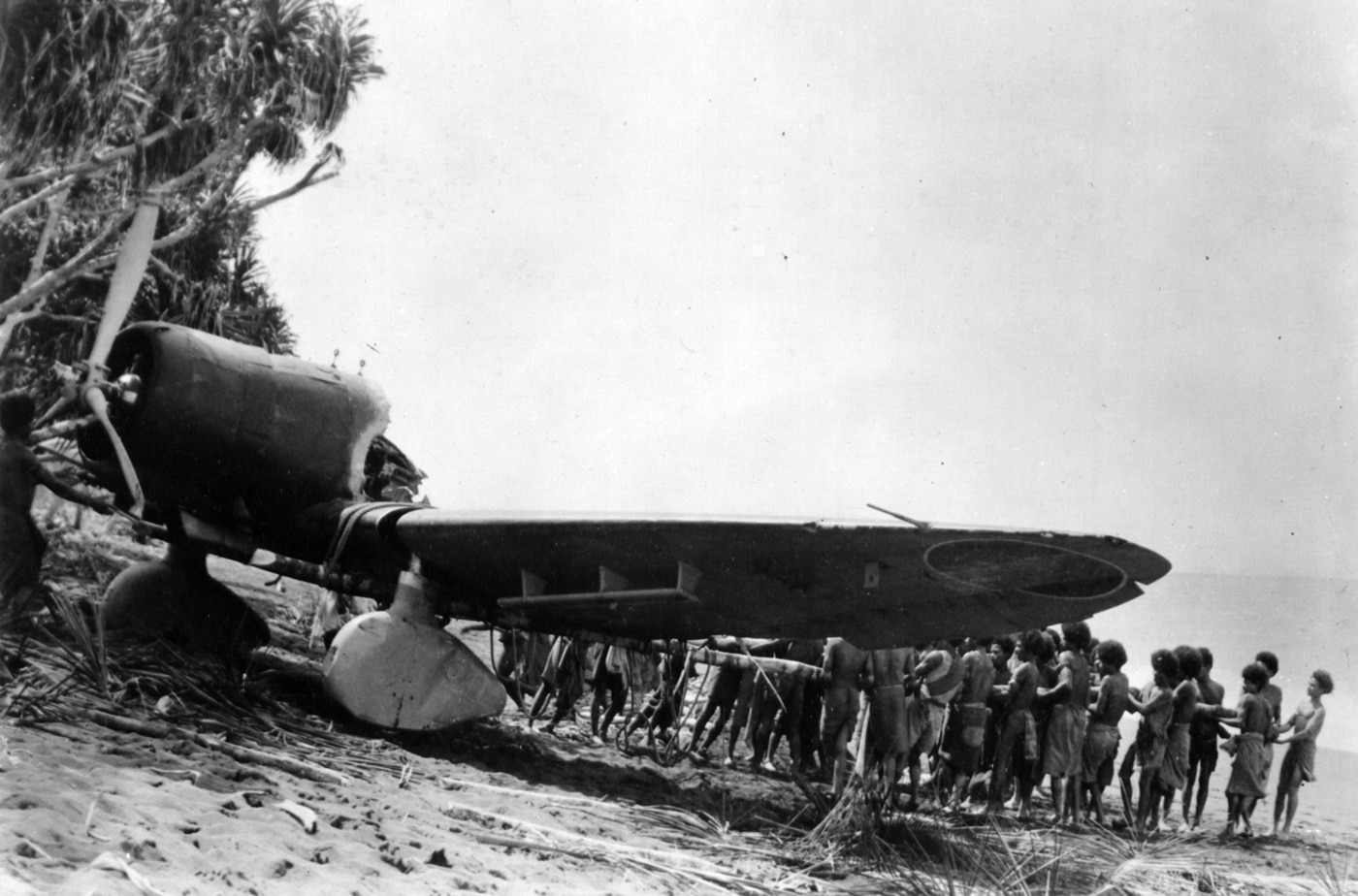 native islanders with Japanese Aichi D3A Type 99 Carrier Bomber Val dive bomber on beach