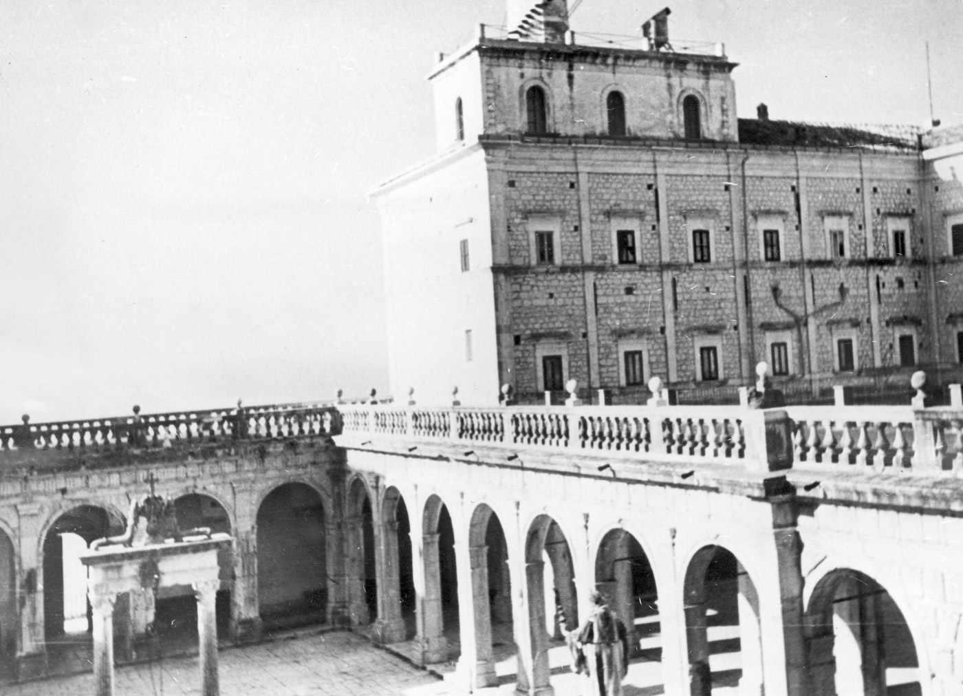 A historic view of the Benedictine Abbey on Monte Cassino Hill, captured before its destruction during the Allied bombing in 1944. The photograph shows the abbey’s original architecture, with part of the courtyard visible, surrounded by the serene landscape of the hill. This pre-war view highlights the abbey’s significance as a center of faith and cultural heritage for centuries. The structure stands intact and majestic, a stark contrast to the ruins it became during the Battle of Monte Cassino. This image serves as a reminder of the profound loss of historic sites during wartime and the importance of their preservation.