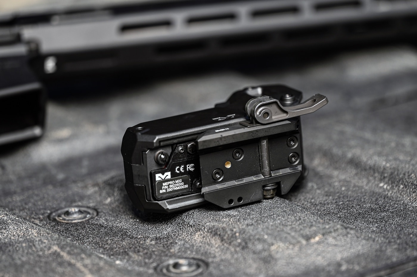 A close-up image of the Meprolight M22 red dot sight's base, clearly showing the quick detach (QD) mounting system. The detailed view emphasizes the locking mechanism and its compatibility with Picatinny rails. The robust design ensures a secure fit while allowing fast removal or reattachment when needed. The compact and efficient mounting system complements the optic's overall durability and ease of use. This shot highlights the engineering precision of the QD system for shooters who value performance and reliability.