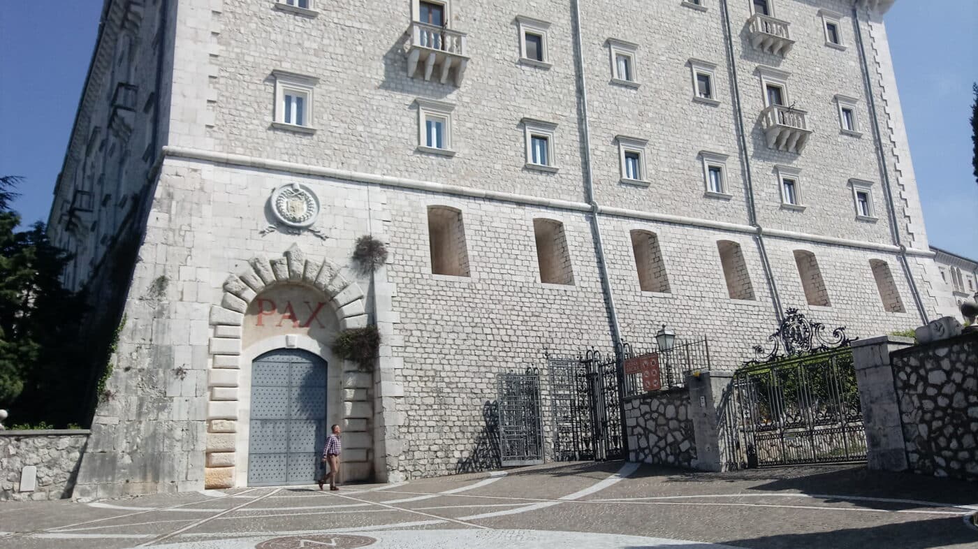 The restored entrance to Monte Cassino Abbey stands as a symbol of resilience and historical preservation following its destruction during the Battle of Monte Cassino in World War II. The modern reconstruction faithfully recreates the abbey's original architectural grandeur, reflecting its significance as a spiritual and cultural landmark. The entrance, surrounded by serene landscapes, contrasts sharply with the devastation it endured during the Allied bombing in 1944. This site now serves as a memorial to the intense combat and the lives lost during the battle. The restored abbey continues to attract visitors, commemorating its role in the Italian Campaign and its recovery from the scars of war.