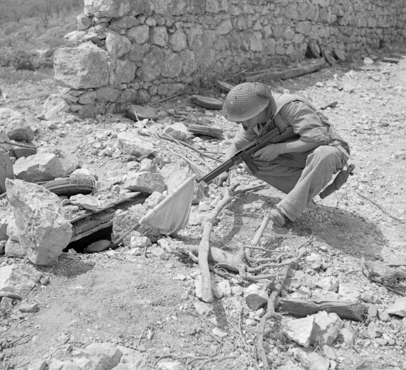 Officer Cadet Jerzy Lesiak of the 6th Armoured Regiment, part of the 2nd Warsaw Armoured Brigade in the 2nd Polish Corps, is shown aiming his Thompson submachine gun at a German sniper during the Battle of Monte Cassino. The sniper, positioned in the ruins of his bunker, signals surrender by waving a white flag. The scene captures a tense yet pivotal moment in the fierce fighting that defined this phase of the Italian Campaign. The rugged and war-torn environment highlights the challenges faced by Polish forces as they advanced on fortified German positions. This image illustrates the bravery and resolve of the 2nd Polish Corps in their critical role in the Allied victory.