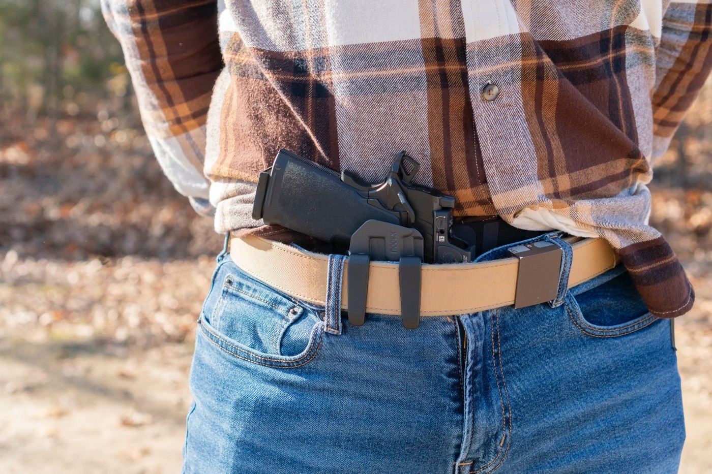 A Springfield Armory pistol is securely holstered in the PHLster Floodlight2, highlighting the holster's universal fit for light-bearing firearms. The holster, designed to index off the weapon-mounted light rather than the firearm, accommodates various pistols with mounted accessories like suppressor-height sights and red dot optics. The photo showcases the sleek ComfortScape design, featuring wave-like grooves for airflow and comfort during concealed carry. The open-ended structure allows for compatibility with threaded barrels and compensators, enhancing its versatility. The sturdy clips ensure a secure attachment to the belt, making it suitable for both appendix and strong-side carry. This image underscores the Floodlight2's innovative features, making it ideal for concealed carriers seeking comfort and adaptability. The pairing of the pistol and holster reflects a focus on practical, high-performance concealed carry solutions.