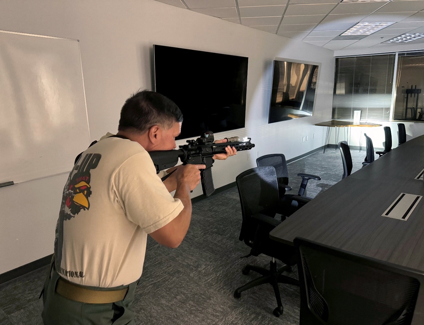 The author illuminates a dark corner of a room with the SureFire Mini Scout Pro flashlight mounted on a Springfield Armory SAINT rifle. The bright 500-lumen output cuts through the darkness, casting a focused beam with a wide peripheral spill for enhanced visibility. The Hybrid Beam Pattern ensures the area is well-lit, allowing for clear identification of potential threats or objects. The flashlight’s ergonomic design enables intuitive operation, critical for maintaining control during tactical exercises. This scene emphasizes the importance of reliable illumination tools in low-light or confined environments.