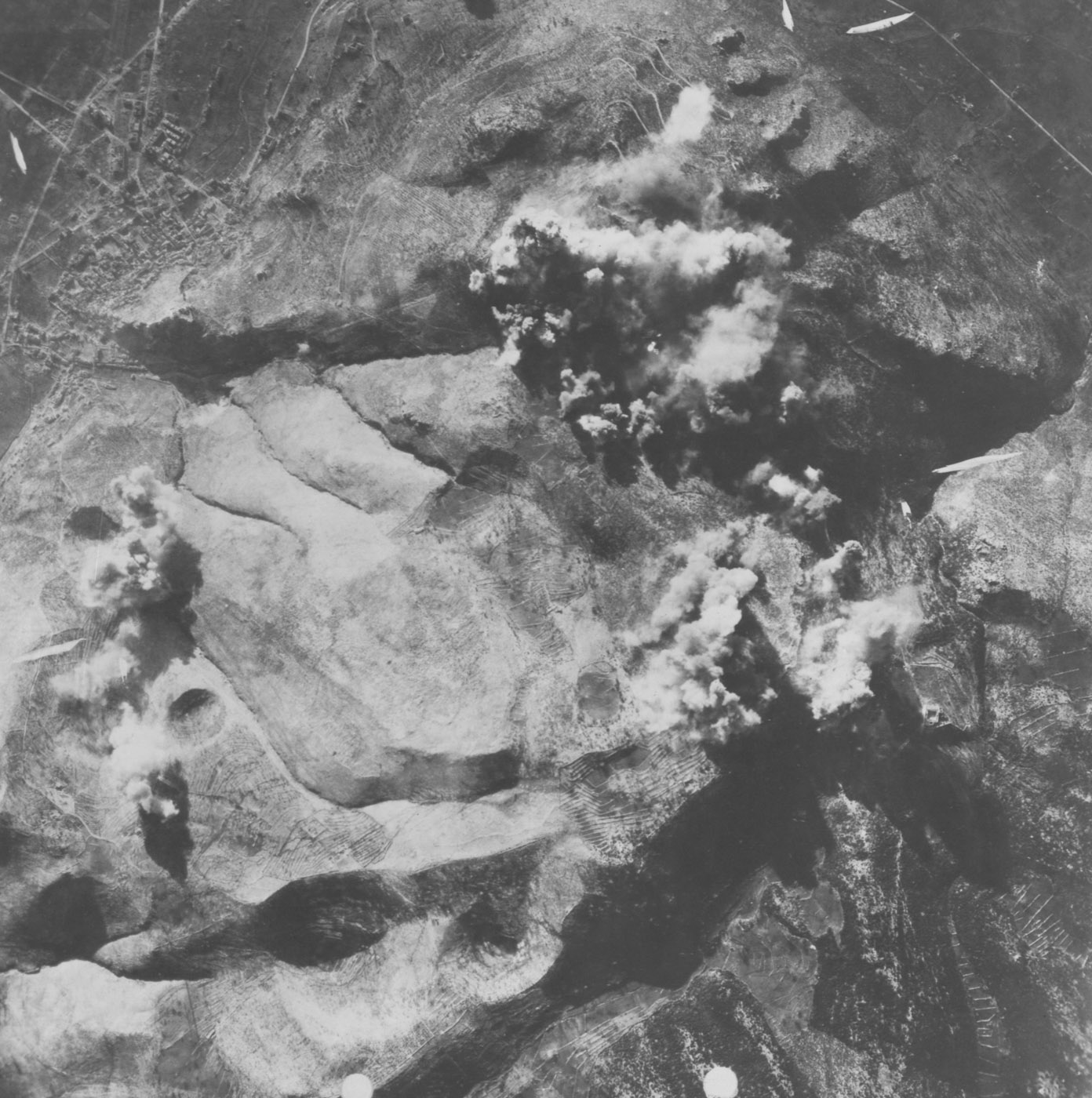 An aerial view captures the explosion at Monte Cassino Abbey during the Battle of Monte Cassino as seen from a Boeing B-17 Flying Fortress in 1944. The photograph shows a massive cloud of smoke rising 1,500 feet into the air, a result of ammunition detonating within the abbey’s east wing. This dramatic moment revealed the use of the historic structure as a fortified German military installation. The bombing involved coordinated strikes by B-17 Flying Fortresses, North American B-25 Mitchells, and Martin B-26 Marauders to weaken the German stronghold on the Gustav Line. The scene illustrates the scale of destruction and the intensity of the Allied campaign to break through German defenses in the Italian Campaign. The image highlights the pivotal role of airpower in one of the war's most contested battles.