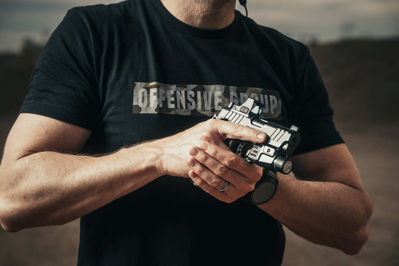 A photo of the author holding the Springfield Armory 1911 DS Prodigy Compact pistol at an outdoor shooting range. The author’s grip demonstrates the compact size and ergonomic shape of the pistol, designed for easy handling. The weapon is equipped with a red dot sight and a Streamlight TLR-7 light, highlighting its tactical versatility. The Adaptive Grip Texture on the polymer frame is visible, providing a secure hold. This image showcases the Prodigy Compact’s balance of compact dimensions and practical features for defensive use.