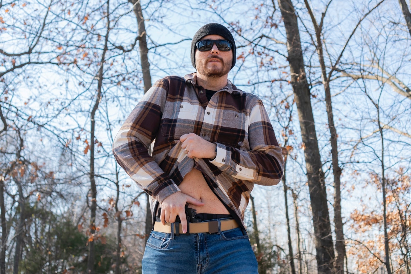 The author is on a shooting range, drawing a Springfield Armory 1911 DS Prodigy pistol from a PHLster Floodlight2 holster worn in the appendix position. The movement highlights the holster's smooth draw and retention capabilities. The holster's ComfortScape texture ensures comfort during carry, even under dynamic conditions. The appendix carry position emphasizes the Floodlight2’s compact design and concealment effectiveness. The universal fit of the holster, designed to accommodate light-bearing pistols, is a key feature being demonstrated. The shooting range backdrop and safety gear underscore the practical testing environment. This photo captures the holster’s performance under real-world conditions. It is also compatible with other pistols like the Glock 17 and Glock 19 handguns.