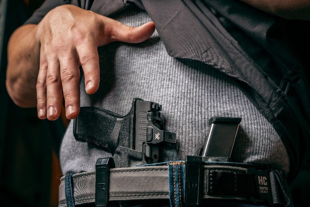 A man reacts to a perceived threat by lifting his shirt and drawing a Springfield Armory self-defense pistol from a concealed holster. His expression is focused, and his body posture suggests urgency as he prepares to defend himself. Many states recognize concealed carry rights, allowing law-abiding citizens to carry a firearm for personal protection. In jurisdictions with Stand Your Ground laws, individuals may legally use lethal force without a duty to retreat when facing imminent peril. The Castle Doctrine also provides legal justification for defensive force, especially in situations involving home defense or unlawful attacks. Courts often evaluate whether the person had a reasonable belief that their life was in danger and whether the use of force was necessary. Prosecutors, defense lawyers, and juries consider various legal factors when determining criminal liability or self-defense immunity. In legal proceedings, concepts like burden of proof, justification, and reasonable doubt come into play when assessing whether a shooting is legally justified.