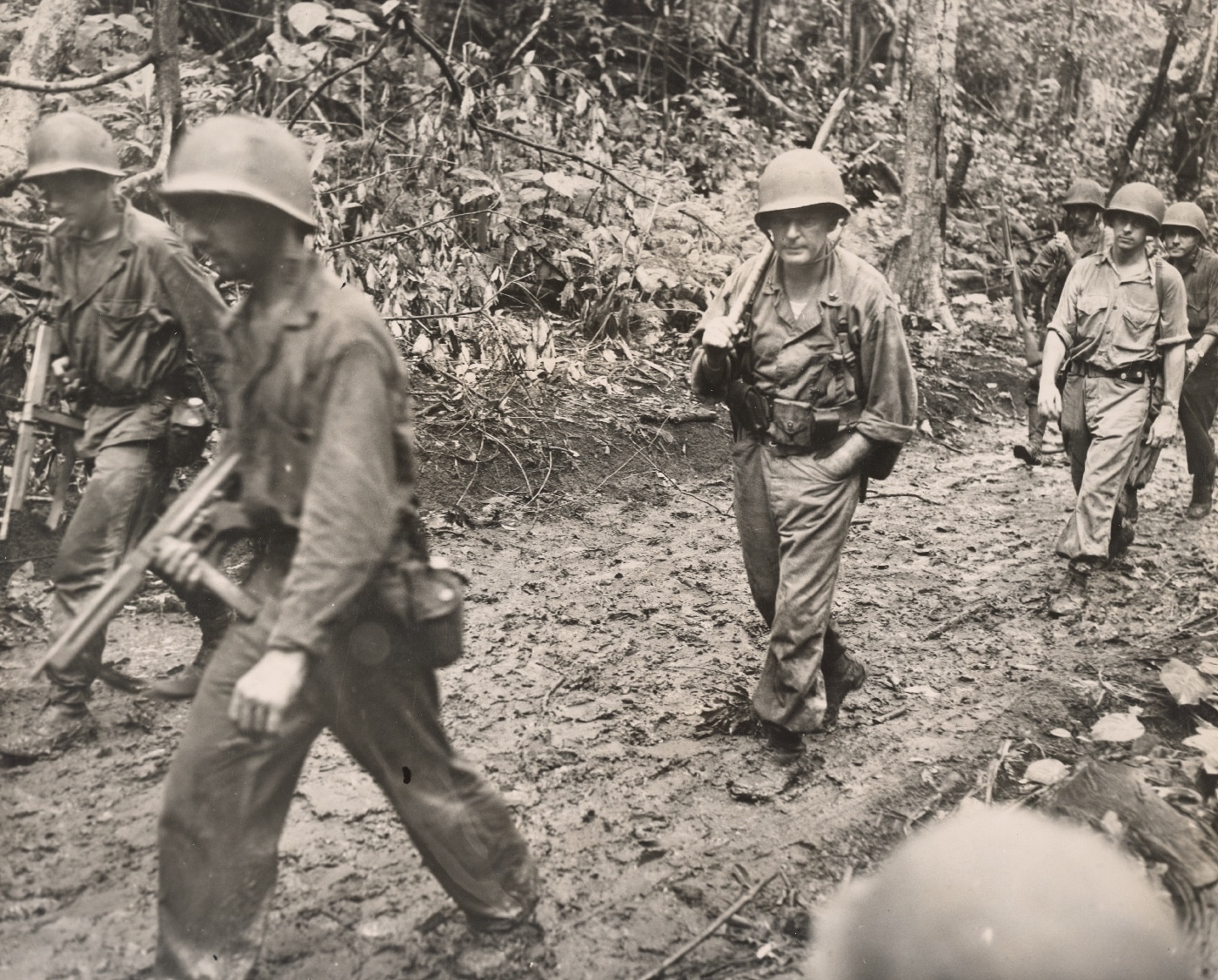 Gen. Lemuel C Shepherd Jr and Marines track down a muddy path on Cape Gloucester