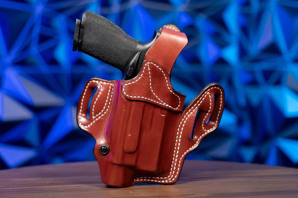 This image features a Springfield Echelon 4.5F handgun with an attached Surefire X300 tactical light inserted into the DeSantis T.B. Vengeance holster. The holster is crafted from premium full-grain steer leather and demonstrates excellent weapon retention with its added thumb break mechanism. It is displayed on a table to emphasize its meticulous stitching and three belt loops designed for multiple carry positions. The setup illustrates features ideal for concealed carry as well as open carry situations. The design highlights key aspects of a unique holster, including minimalist design and additional strength from its wraparound band. Keywords such as holster, handgun, pistol, concealed carry, thumb break, and premium leather holster are central to this review. The photo serves as a detailed visual guide for anyone interested in quality firearm retention and modern holster engineering.