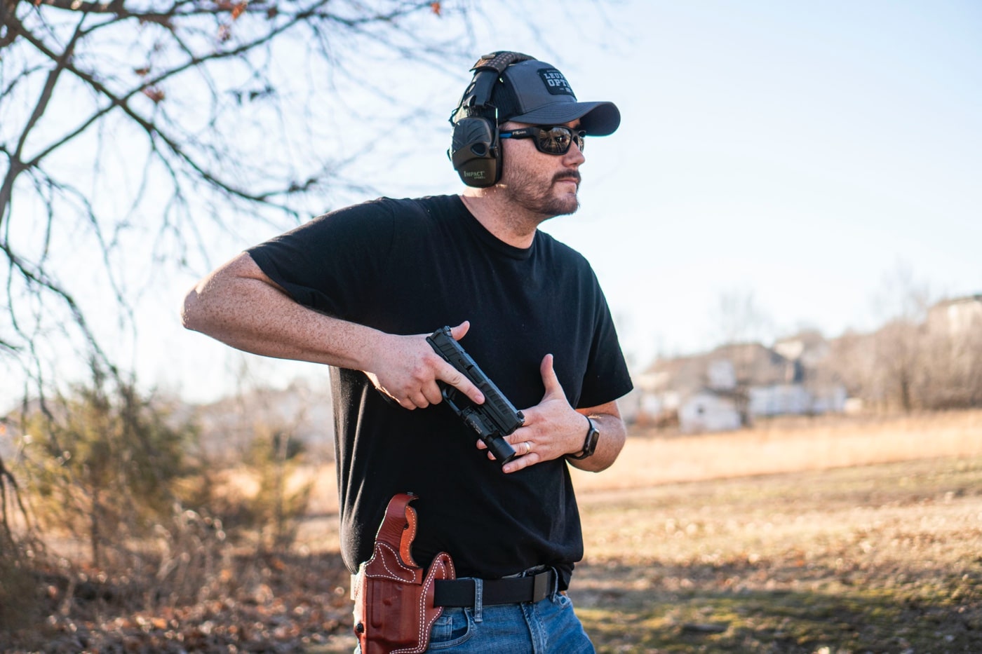 This image shows the author at a shooting range drawing a Springfield Echelon pistol from the DeSantis T.B. Vengeance holster. The photograph captures the holster’s precise retention mechanism, including the innovative thumb break design. It highlights the premium American full-grain steer leather and meticulous stitching that ensure excellent durability. The scene illustrates the practical application of the holster in both concealed carry and open carry scenarios. The author’s testing emphasizes the ease of drawing and secure firearm retention essential for real-world shooting. Keywords such as holster, handgun, pistol, concealed carry, thumb break, premium leather holster, review desantis, and scabbard holster are incorporated to support the review. This detailed description is intended to guide visually impaired users in understanding the holster’s advanced features and practical performance.