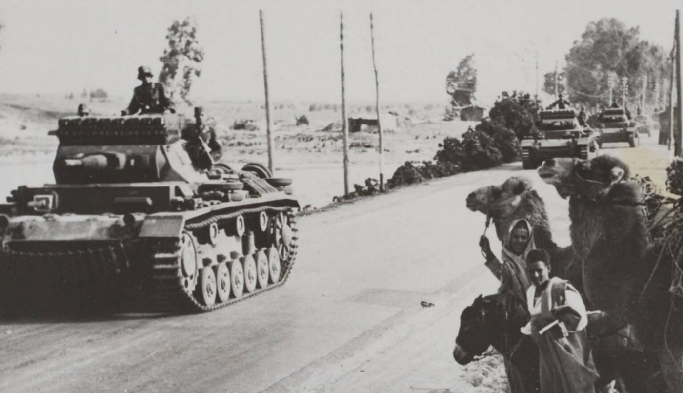 This image captures German Afrika Korps Panzer III tanks, also known as Panzerkampfwagen III, advancing across the North African desert. The robust pz iii vehicles, with their prominent turrets and rolled homogeneous armour, showcase the engineering prowess of Rheinmetall and the strategic innovation of Nazi Germany’s armored forces. In the background, Libyans on horseback and riding camels observe the mechanized advance, highlighting the stark contrast between traditional modes of transport and modern armored warfare. The scene vividly illustrates the integration of panzer divisions and blitzkrieg tactics, pivotal in campaigns of World War II. The interplay of modern tank design and indigenous culture offers a dynamic glimpse into the diverse challenges of the North African theater. This historic portrayal underscores the significant role of mechanized troops and armored fighting vehicles in shaping the course of military history.