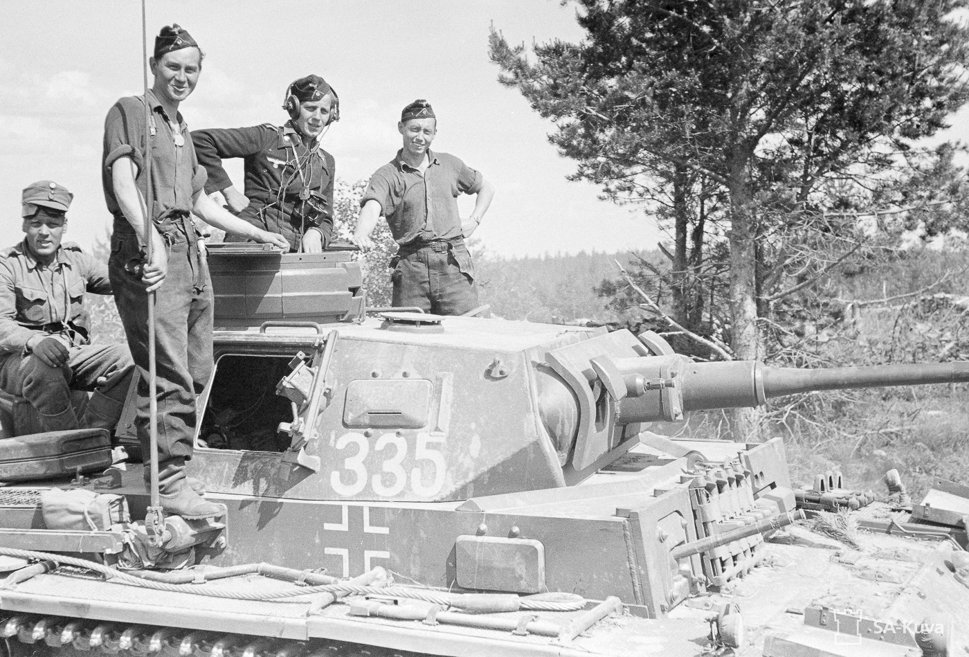 This image shows a German Panzer III tank, also known as Panzerkampfwagen III or pz iii, pausing with its crew during an advance through the villages of Vienna Karelian in Finland. The tank’s detailed turret, main armament, and rolled homogeneous armour reflect the engineering expertise of Rheinmetall and the operational strength of German armored forces. The scene captures a moment of tactical pause amid the movement of panzer divisions, emblematic of the blitzkrieg approach and mechanized troops of the Wehrmacht. In the background, the quaint village setting contrasts with the formidable presence of this armored fighting vehicle, reminiscent of the dynamic operations seen during World War II in various theaters including Kursk and Stalingrad. This portrayal emphasizes the critical role of the Panzer III in the evolution of armored warfare and the broader historical impact of Nazi Germany’s panzer divisions.